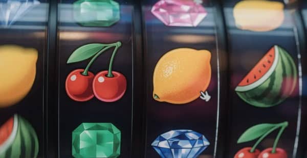 The image features vibrant slot machine reels adorned with various fruit and gem symbols, inviting players to engage in online slot games. This colorful display represents the excitement of casino games, where players can win real money and take advantage of generous bonus offers, such as free spins and deposit bonuses.