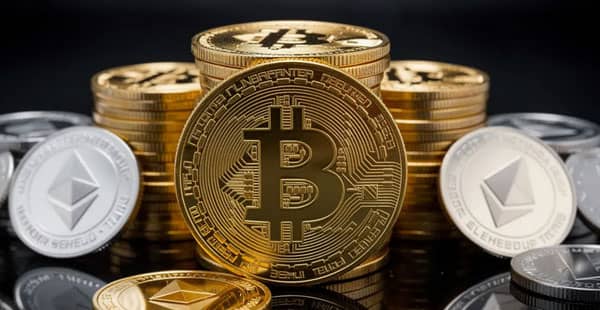 The image features a collection of golden Bitcoin coins stacked next to Ethereum and Litecoin coins, all resting on a dark reflective surface. This visually striking arrangement highlights the allure of cryptocurrency, often associated with online crypto casinos and the growing crypto gambling market.